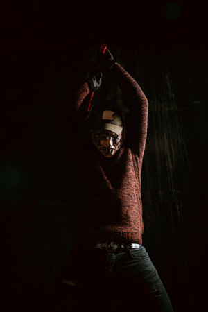 Horror character wearing mas and holding chainsaw, Halloween scary scene.