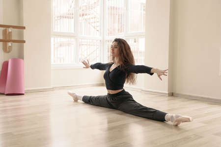 Beautiful slim girl engaged in fitness in studio, doing stretching at class