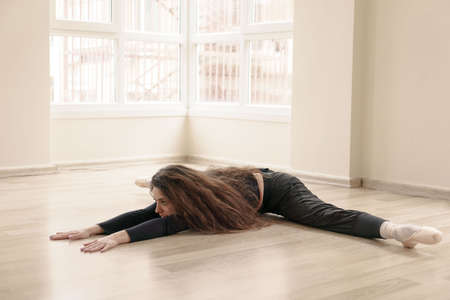 Beautiful slim girl engaged in fitness in studio, doing stretching at class