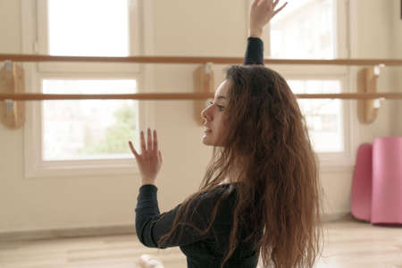 Beautiful slim girl engaged in fitness in studio, doing stretching at class