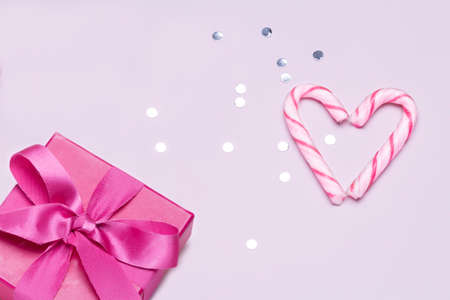 Pink gift with candy cane and silver confetti. Concept to love and friendship, celebrate and congratulate.Copy space for advertising.の写真素材