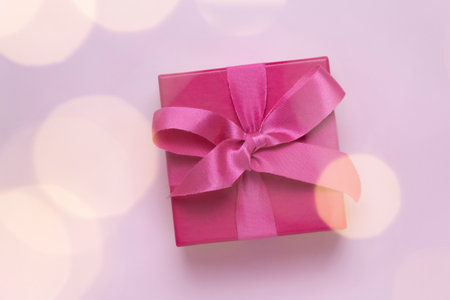 Pink gift with pink gift with christmas lights bokeh in front. Copy space for advertising. Concept...