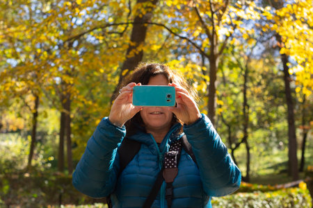 Women taking photos with mobile phone, selective focus in nature on an autumn day.の写真素材