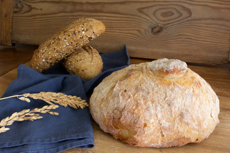 Delicious and freshly baked traditional big round bread close up and two roll bread cereals on the background. Horizontal view.の写真素材