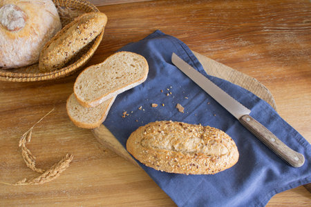Bread on a cutting board and a knife on a wooden tableの写真素材