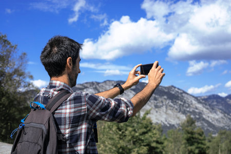 Hiker with backpack takes photo whit his phone of the mountains of the Urkiola Natural Par in the Basque Country, Spain.の写真素材