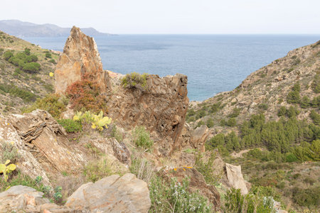 A rocky hillside overlooking a body of water. The view is serene and peaceful, with the ocean in the distance and the rocks providing a sense of stability and strength. Girona, Spainの写真素材