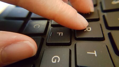 Close upp distorted view of caucasian fingers typing on a qwerty keyboard