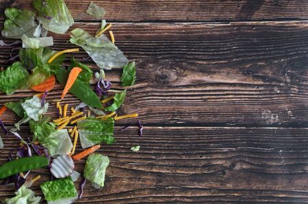 Components of a vegetable salad to the left, with wooden background and copy spaceの写真素材