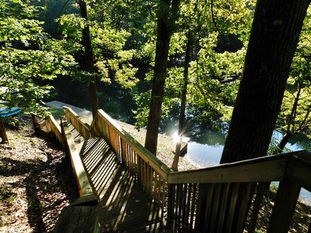 View looking down the stairs to the boat dock by the lake, with the morning sun reflecting off the water, at Blue Mountain Camp in Hamburg, Pennsylvaniaの写真素材