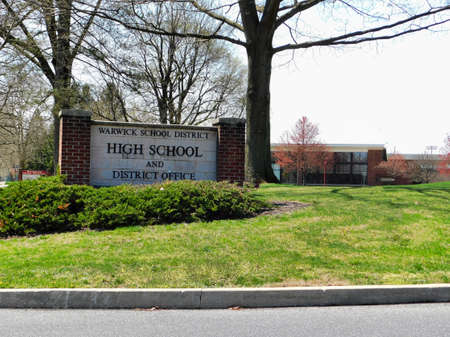 The Warwick school district and high school sign, with Warwick high school building in the background, near Lititz, Pennsylvania.  Taken April 13th, 2019 around 1:45 pmのeditorial素材