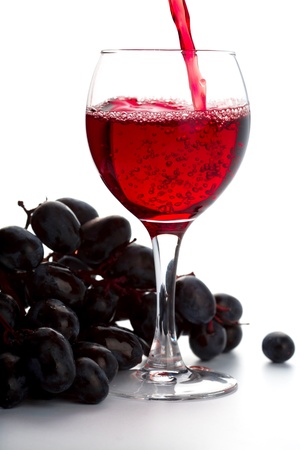 grapes and red wine in a glass isolated on white backgroundの写真素材