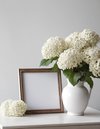 White hydrangea flowers in vase and photo frame on white tableの素材