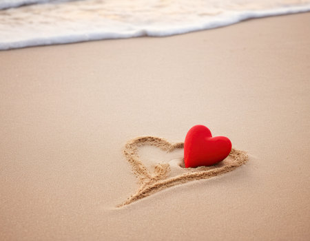 Red heart on the sand beach with sea wave. Valentines day backgroundの素材