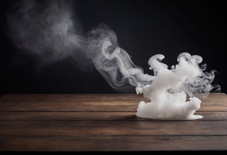 White cloud of smoke on a wooden table against a black background.の素材