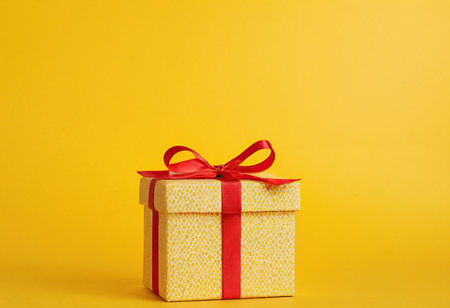 Gift box with red bow on yellow background. Copy space.の素材