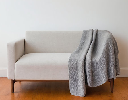 White sofa with gray blanket on wooden floor in empty room interior.の素材