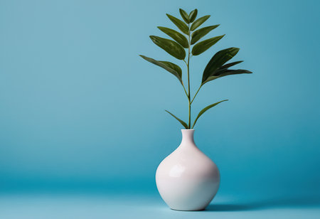 White vase with a plant on a blue background. Minimal concept.の素材