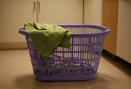 Laundry basket with a green towel on the floor at homeの素材