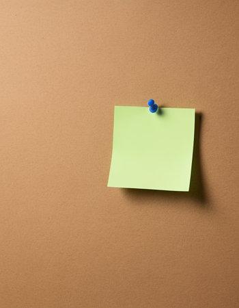 sticky note with thumbtack on brown background. copy spaceの素材
