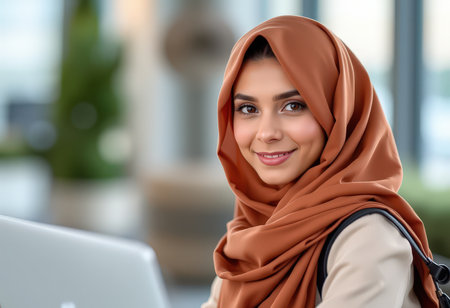 Portrait of young muslim businesswoman with hijab working on laptop at officeの素材