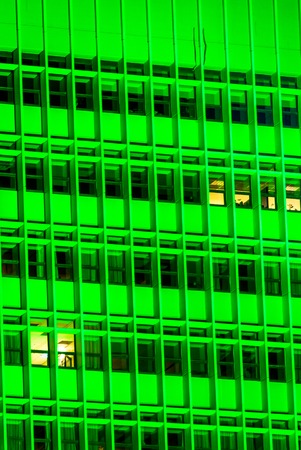 vertical Green of a tall building with windows at nightの写真素材