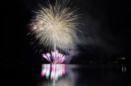 Celebration with colorful fireworks show with rockets bursting above the lakeの写真素材