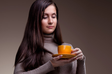 Beautiful happy young woman  with cup of aromatic coffee or tea on natural backgroundの写真素材