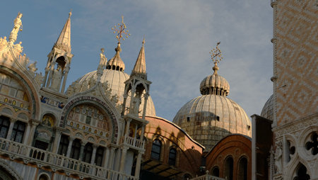St. Mark's Basilica showcases magnificent architecture with intricate domes and spiers in Venice, bathed in warm sunlight during the late afternoon.の写真素材