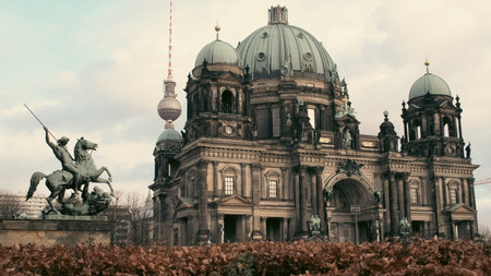 A grand historic structure featuring a large dome stands prominently in Berlin. In front, a heroic statue of a rider on a horse adds to the architectural beauty against a cloudy sky.の写真素材