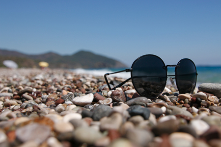 Sunglasses on a pebble beach by the seaの写真素材