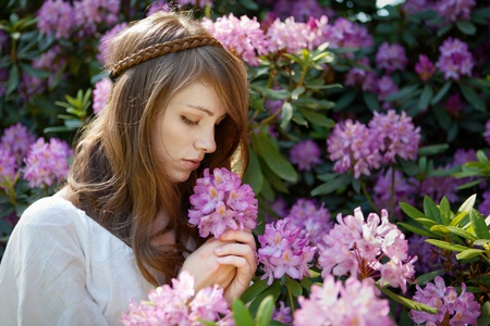 A young lady enjoys the smell of a rhododendron  blossom の写真素材