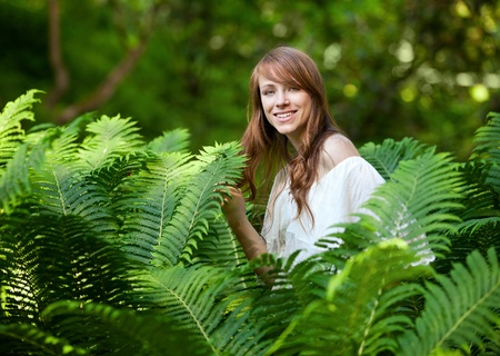 A young, beautiful lady hides and seeks in fernの写真素材