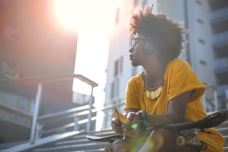 Skater girl is listening to musicの写真素材