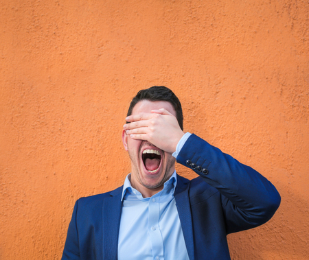 Businessman is covering his eyes and open his mouthの写真素材