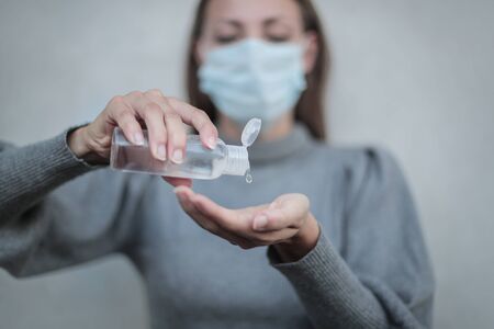 Woman wearing a face mask and using a hand hand sanitizerの写真素材