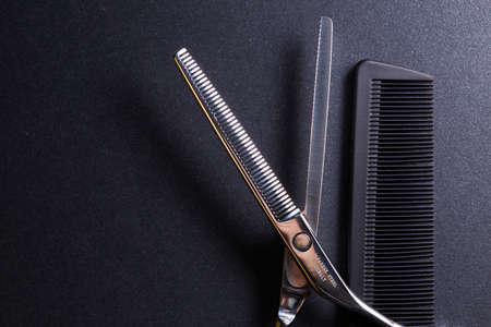 japanese professional hairdressers thinning scissors and comb on black background. Beauty salon equipment. Stylish Professional Barber, Haircut accessories.の写真素材