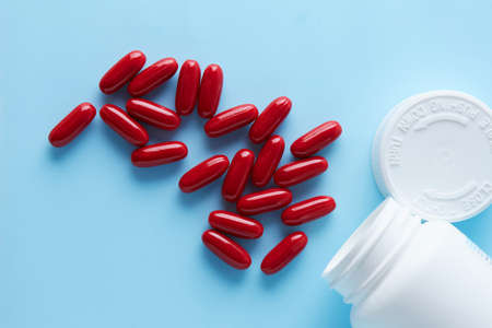 red capsules pill spread on blue background with shadow . Global healthcare concept. Antibiotics...