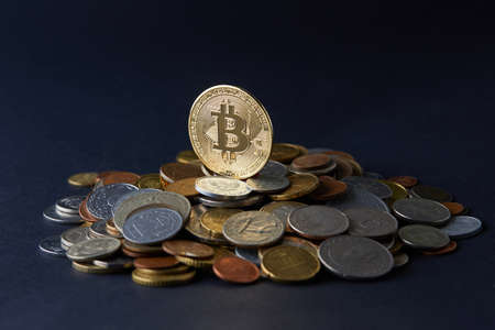 Golden and shiny bitcoin coins on top of various world currencies representing a choice of different payment and investment options.の写真素材