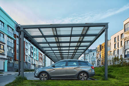 New Metal Carport for public vehicle parking in Front of Multi residential Building. outdoor parking lot with car.の写真素材