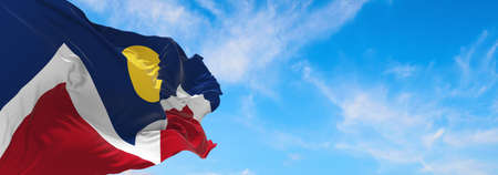 flag of Denver, Colorado at cloudy sky background on sunset, panoramic view. Patriotic concept about Denver, Colorado and copy space for wide banner. 3d illustration.の写真素材