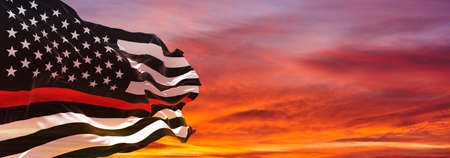 Thin Red Line. Black Flag of USA with Firefighter red Line waving in the wind on flagpole against...