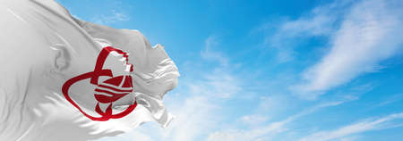 official city flag of Sagamihara, Kanagawa waving in the wind on flagpoles against sky with clouds...