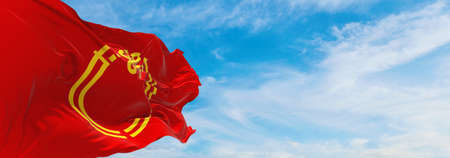 official flag of Niigata prefecture waving in the wind on flagpoles against sky with clouds on sunny...