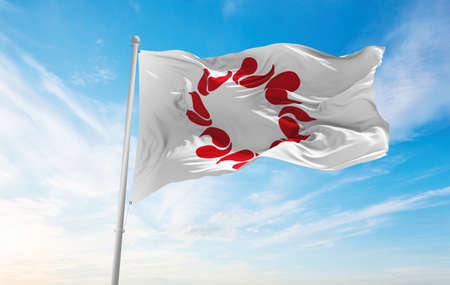 official flag of Saitama prefecture waving in the wind on flagpoles against sky with clouds on sunny...