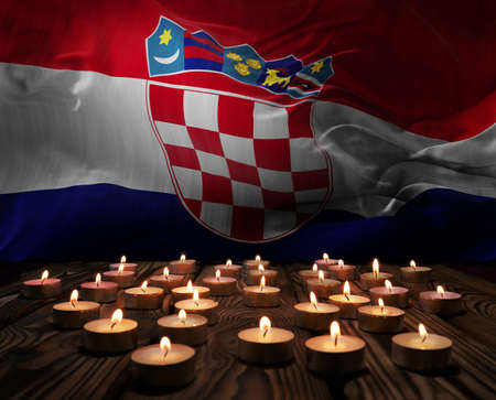 Mourning candles burning on Croatia national flag of background. Memorial weekend, patriot veterans day, National Day of Service Remembrance. Burning candles on wooden surface. 3d illustration.の写真素材