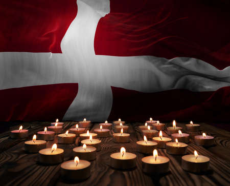 Mourning candles burning on Denmark national flag of background. Memorial weekend, patriot veterans...