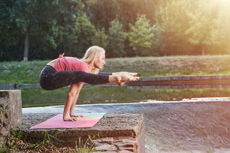 young Sport blond woman yogini practice yoga exercise in park on evening, sunset. yoga is meditation and healthy sport concept.の写真素材