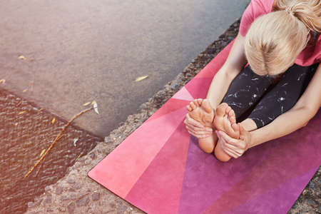 young Sport blond woman yogini practice yoga exercise in park on evening, sunset. yoga is meditation and healthy sport concept.の写真素材