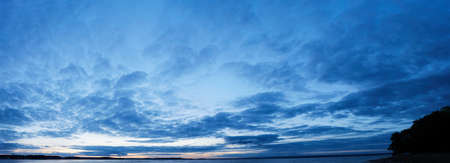 Panorama of Calm evening sky with clouds. Sky background after sunset. Sunrise sky with lighted clouds, Beauty evening sunrise over seaの写真素材